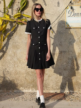 a lady wears a little black dress with peal buttons design